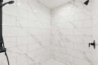 Walk-in shower with stunning marble detailing and matte black finishes.