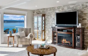 Living room boasts waterside views and cozy fireplace.