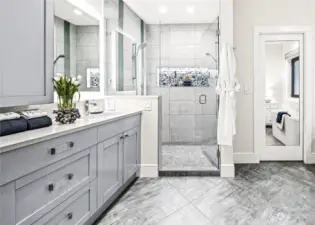 The beautifully remodeled primary bath enjoys a double shower with custom LED niche lighting, a soaking tub, a double vanity with slab quartz countertops, lighted mirrors, and heated floors.