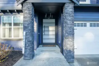 Covered entrance with upgraded stone pillars, custom grand door and chandelier welcomes you in.