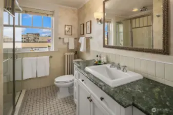 The beautifully remodeled primary bath is tucked discretely behind the dressing area.