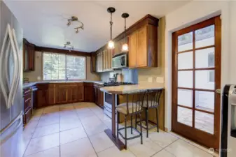 Lots of light in this tile/cherry wood kitchen with breakfast bar.