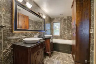 Elegant marble tile primary bathroom with double sinks, jetted tub and separate shower.