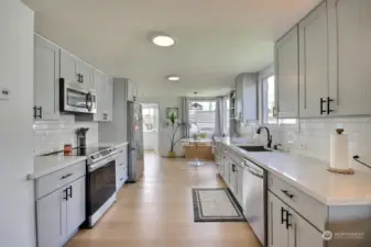The chef's kitchen features quartz countertops, subway tile backsplash, shaker style cabinets that offer lots of storage.  The stainless appliances stay!