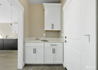 Upper & lower cabinets plus laundry sink on one side of utility