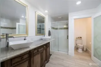 Primary bathroom with 2 sinks, walk-in tile surround shower, toilet closet, tub and linen nook. Tile floors.