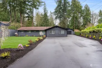 Long asphalt driveway entrance, lots of parking, and with beautiful landscaping on either side.
