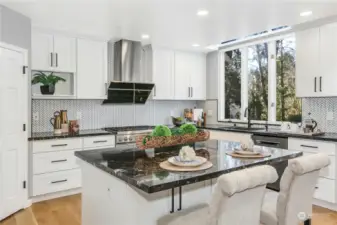 Gourmet kitchen with an open, great-room layout. Granite center island + countertops.The KitchenAide refrigerator/freezer is brand new (March 2024).  Custom cabinetry & backsplash, butler's pantry with beverage cooler + a spacious walk-in pantry for abundant storage.