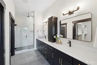 Luxurious primary bathroom with double vanity, elegant tiled walk-in shower.