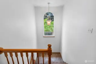 Large arched window brings nature and natural lighting into the stairwell.