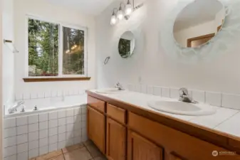 Dual sinks in Primary Bathroom with tile counters and unique individual mirrors. Plenty of vanity storage. Soak your troubles away in deep tub.