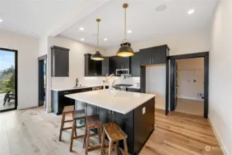 Love this kitchen with wood flooring, white quartz counters, spacious island, stainless appliances, white tile backsplash. (Laundry room to the right)