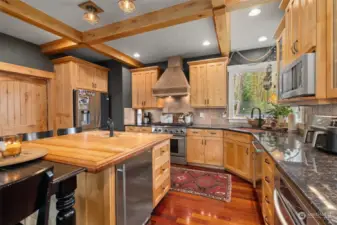 Maple wood kitchen island with sink and stainless steel appliances.