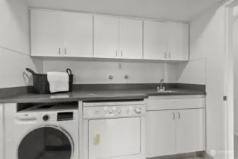 Full-size washer and dryer in the laundry area, which also includes extra storage and a utility sink for added functionality