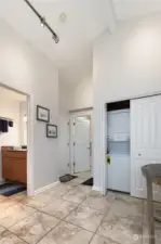 Another view of the entrance to the home showing the washer and dryer, hallway full bath to the left of the photo and doorway to the primary suite & bath featured in the back of the photo.