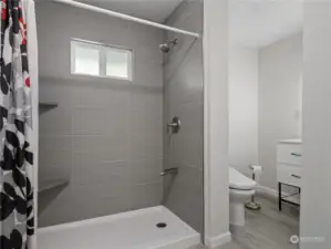 Beautifully updated bathroom features laminate flooring and a large shower with shelving.
