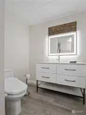 The updated bathroom has a beautiful vanity and a lighted mirror.