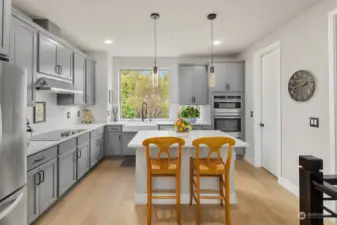 Lovely spacious kitchen includes custom lighting and quartz countertops.
