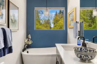 Primary bathroom soaking tub with calming view out to trees.