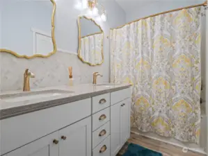 Updated full bath has a dual sink vanity with new quartz and marble backsplash and a tub/shower combo.