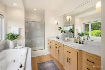 Bright and luxurious primary bath with solid countertops, double vanity, jetted tub, walk-in shower, and private water closet