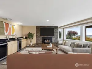 Downstairs family room with 2nd propane fireplace, another fantastic wall of windows, wet bar & mini & wine fridge. To the right of fp is dog door providing access to fully fenced S side of home.