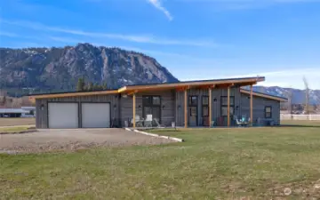 Enjoy panoramic views from all sides of the home. This perspective captures the rear of the house, highlighting the oversized two-car garage intentionally elongated to accommodate larger vehicles or trucks.