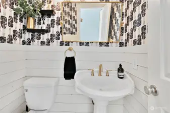 The updated guest / powder half bath is decorated with designer shiplap and located off the family room, near the man-door entrance to the 2-car attached garage with storage racks and overhead storage system.
