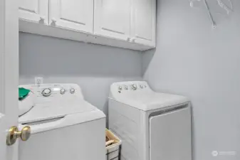 The laundry room is located just off the hallway near the primary bedroom for easy access, with extra storage cabinets.