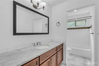 The main bathroom has tile accents, tile surround for the tub as well as tile flooring. The quartz counter really adds to the brightness. Newer fixtures here too!