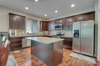 Spacious kitchen with large granite island with full tile backslash.