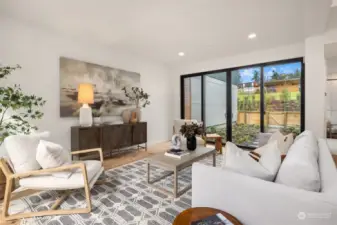 The spacious living room provides access to both the front patio and back garden through large sliding glass doors, creating a seamless indoor-outdoor flow that enhances the sense of space and natural light.