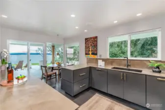 Fully updated kitchen features charming breakfast nook with views and top-of-the-line design details including sleek floating counters of Neolith sintered stone and solid maple diamond soft-close cabinetry. German-made Blanco silgranit sinks