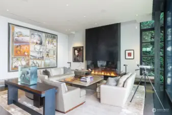 Main level great room living area, steel and glass fireplace, built-in seating, venetian plaster walls, steel and oak plank flooring, walls of windows.