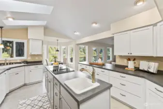 Filled with light thanks to skylights and vaulted ceilings, the kitchen has loads of cabinetry and prep space and is its own delightful space
