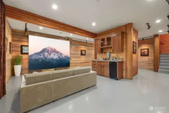 Virtually staged to show what a great movie room this could be, Small fridge with wet bar. Other side of bar is wood stove