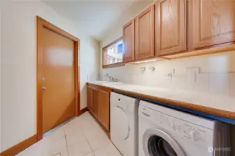 Laundry room, with full size sink,  tile counters and back splash. Bosch washer and dryer.  Garage entry door.