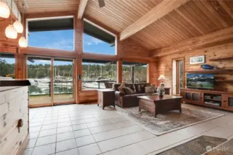Living room with custom wood and open wood beam ceilings, Porcelain tile floors. Pella sliding glass door opens to entrainment size deck with glass wind screen.  Huge windows with views of the water, marina, and surrounding treed hills.
