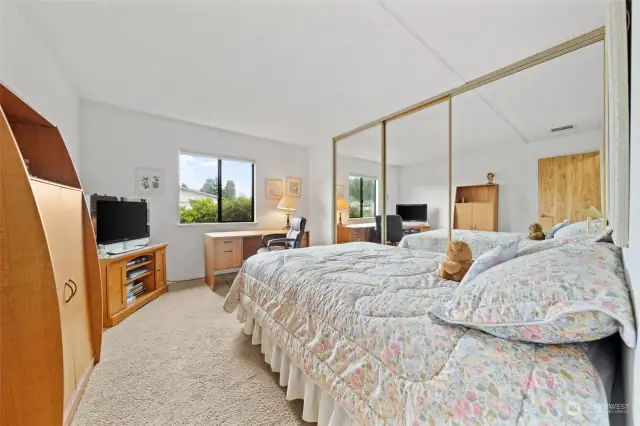 Bedroom with large mirror closets, carpet and window.