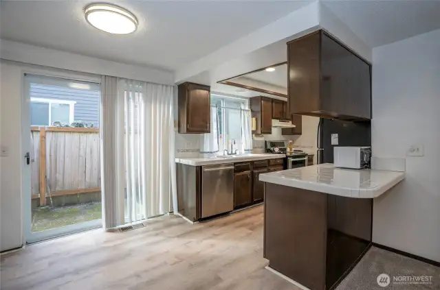 View from the family room into the kitchen, featuring a second sliding door that opens to the side of the home with a walkway leading to the backyard or to the gate providing access to the front yard.