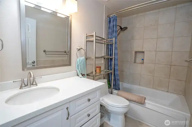 The beautifully remodeled main guest bath offers a jetted tub, cozy heated floors, and sleek quartz counters for added luxury.