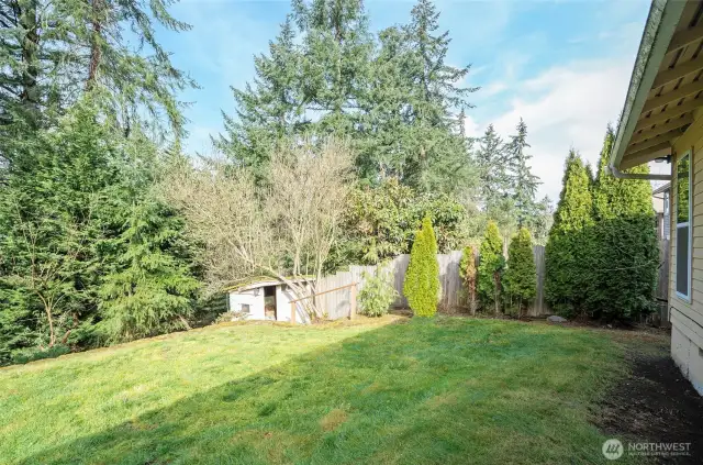 Fully fenced backyard with a storage shed tucked in the corner for added space.