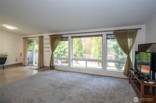The living area is enhanced by a wall of windows overlooking the private backyard and generous deck—perfect for indoor-outdoor living.