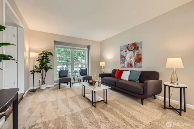 Comfortable living room with large front-facing windows and plush carpet. Open and airy layout offers excellent natural light.