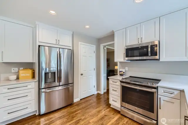 Kitchen features stainless steel appliances, including French door refrigerator and glass-top range. White cabinetry with brushed nickel hardware offers abundant storage.