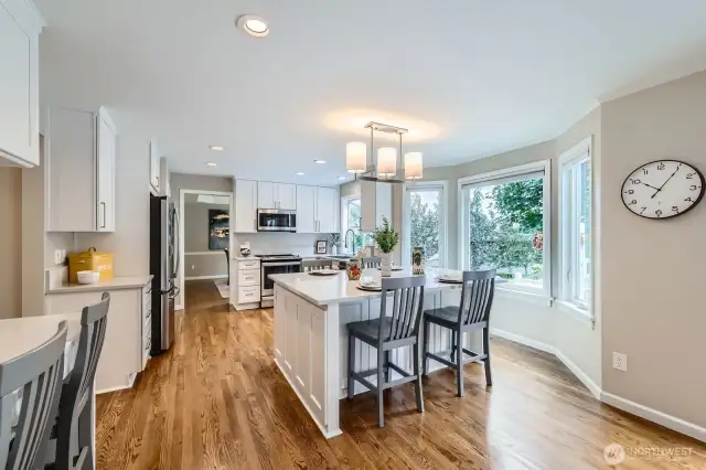 Bright eating area with wraparound windows and views of the backyard. Kitchen island provides extra prep space and seating for casual dining.