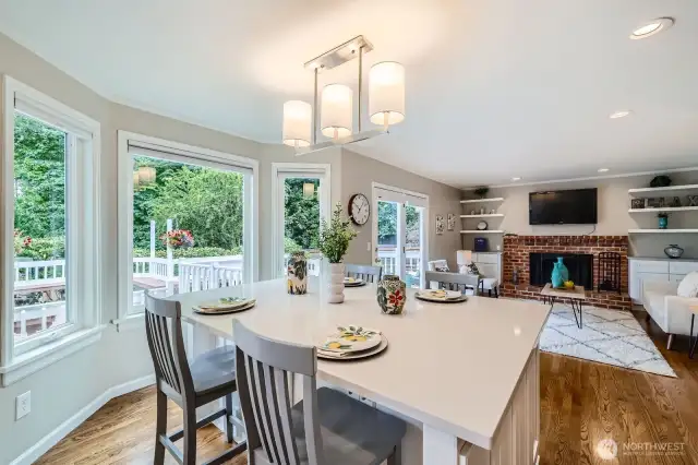 Island kitchen with quartz counters and pendant lighting opens to family room. Multiple windows create a light-filled space ideal for everyday living.