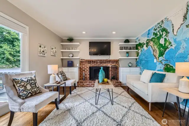 Brick-surround fireplace is the focal point of this cozy family room. Built-in cabinetry and open shelving provide functional storage and display space.