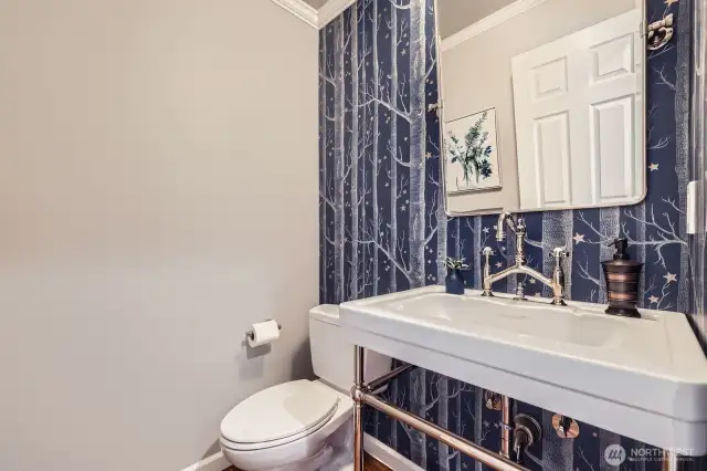 Main floor powder room features designer sink, custom wallpaper accent wall, and updated fixtures.