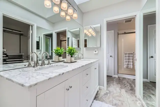 The ensuite bath impresses with a quartz marble dual vanity, contemporary lighting, and a skylight that enhances the spa-like atmosphere.